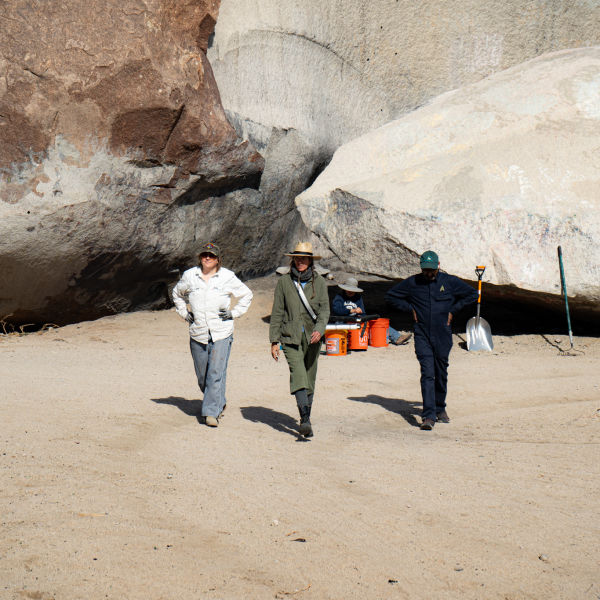 Three people walking away from Giant Rock during 2025 clean up